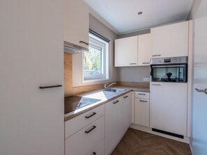 Eine moderne Küche mit weißen Schränken, einem Einbauofen und einem Fenster, das für natürliches Licht sorgt.