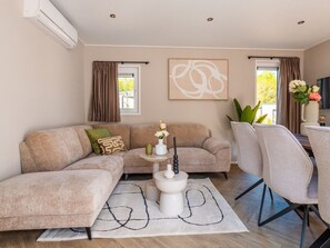 Ein modernes Wohnzimmer mit einer Eckcouch, einem Couchtisch und einem Fernseher.