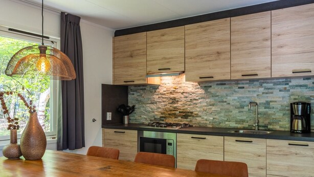 Una cucina moderna con zoccolo in pietra, mobili in legno e un'area pranzo con tavolo e sedie in legno.