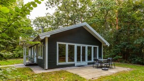 Una casa moderna con un portico coperto, ampie finestre e un giardino.