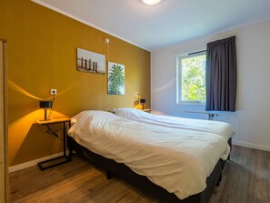 A bedroom with a bed, bedside tables, a lamp, a window with curtains, and two wall-mounted pictures. - De Wiltzangh - Vennenborg Lodge | 6p by Interhome (Ruinen)