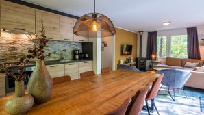 Una cocina moderna con salpicadero de piedra, un comedor con mesa y sillas de madera, y una sala de estar con sofá y chimenea.