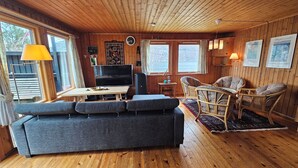 A cozy cabin interior with a sofa, a table, a television, and a fireplace.