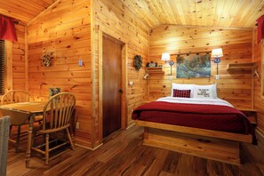 L’intérieur d’un chalet en bois, avec un lit, une table et des chaises.