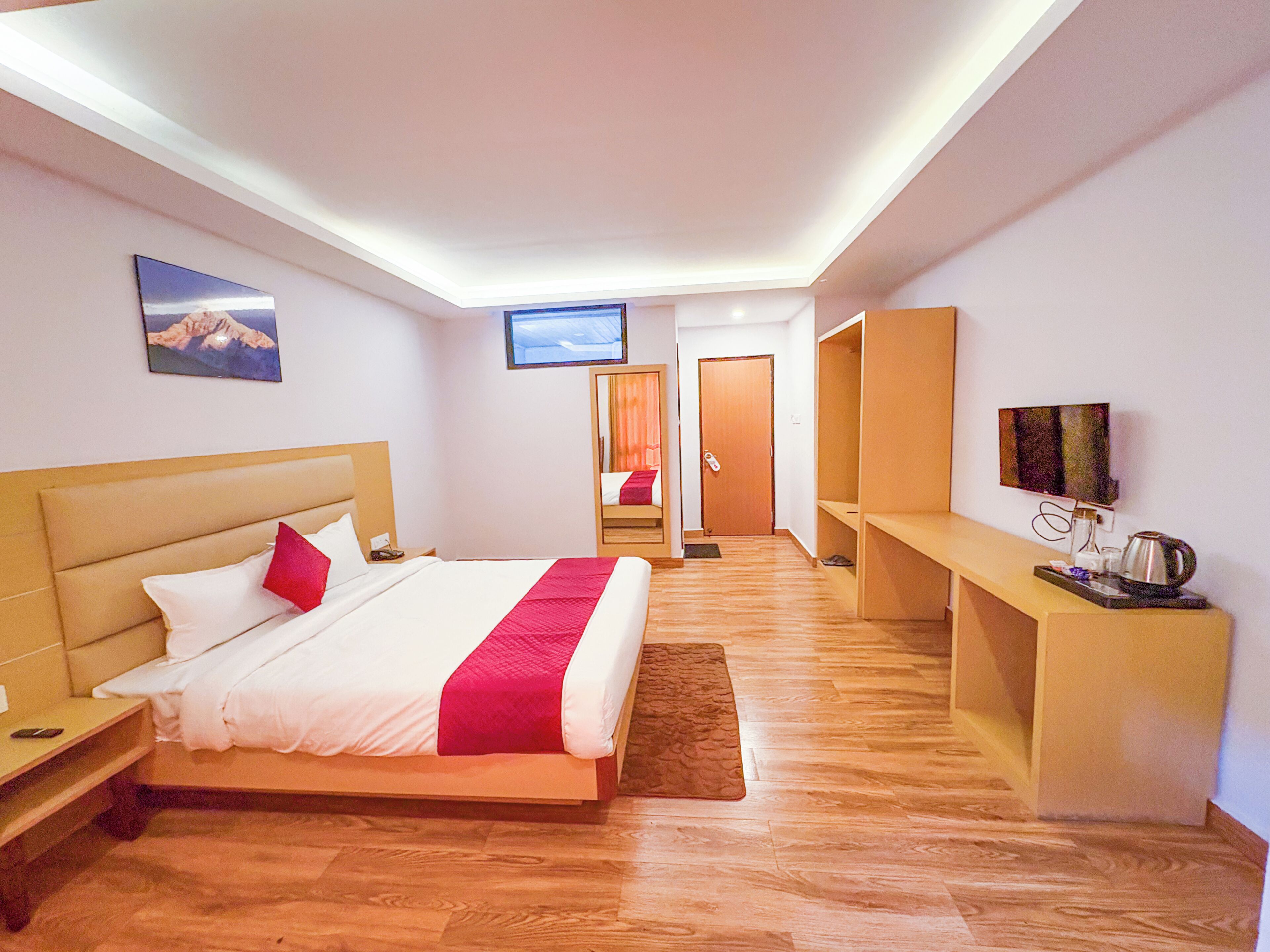 A hotel room with a bed, a TV, a desk, and a mirror.