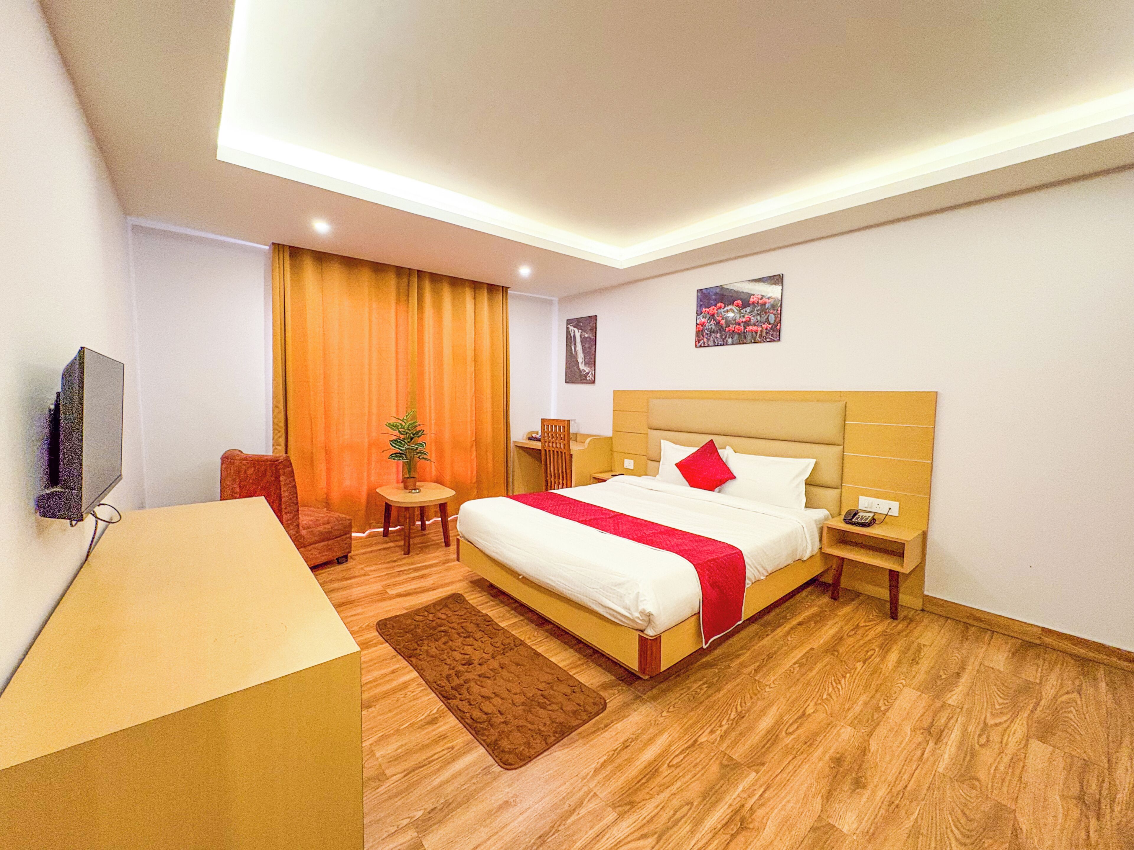 Una habitación de hotel con cama, mesita de noche, silla, escritorio y televisor.