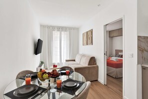 A modern hotel room with a dining area, a sofa, and a bed. - Branded New - Well Designed - 2 rooms Apt in Paris 20 (Paris)