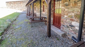 Ein Steinhaus mit einer Holzveranda und einer roter Tür.