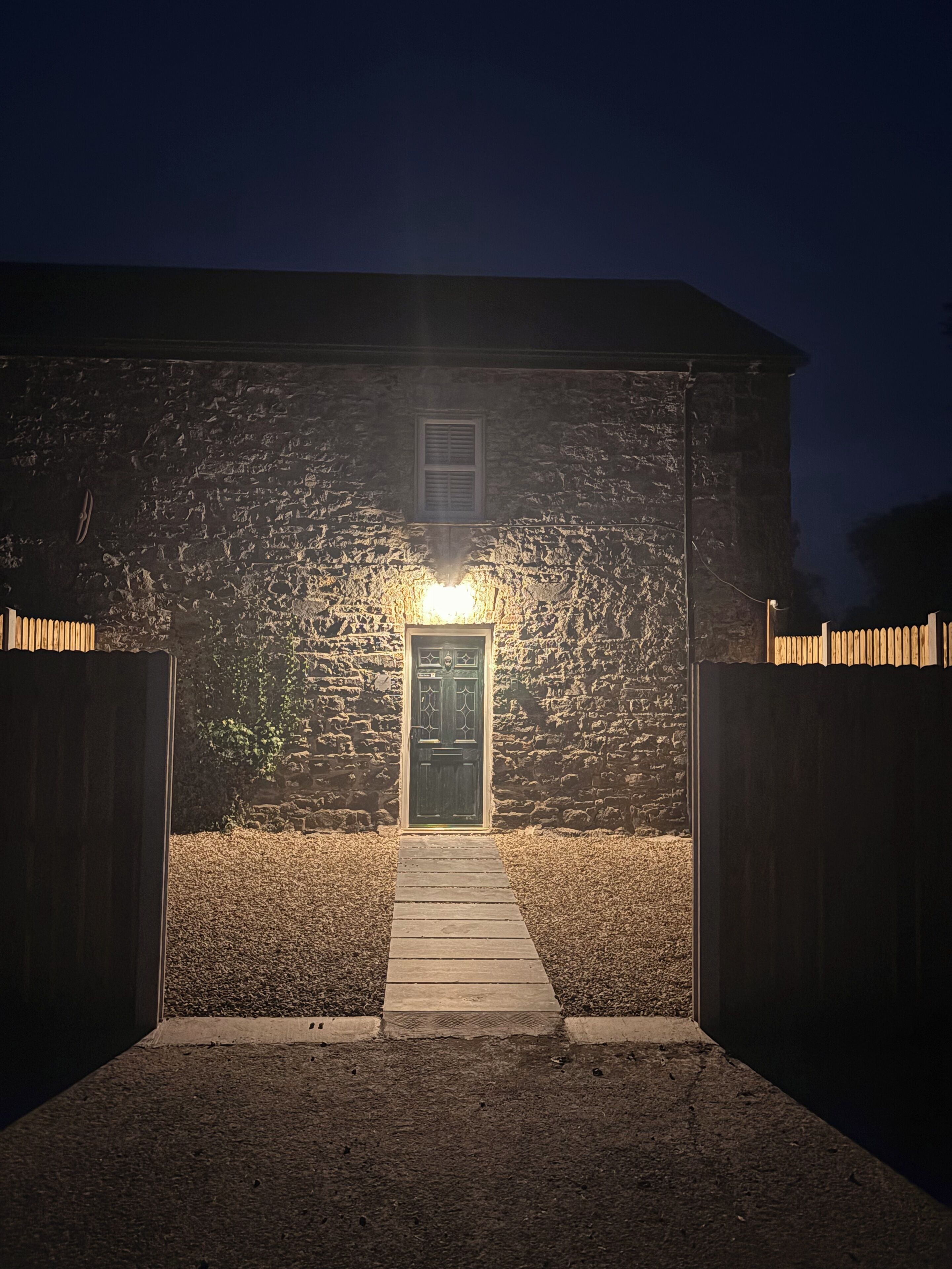 A stone building with a wooden door and a pathway leading to it.
