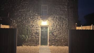 A stone building with a wooden door and a pathway leading to it.