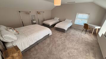 A bedroom with two beds, a desk, and a chair.