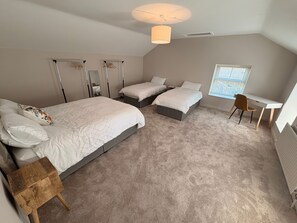 Un dormitorio con dos camas, un escritorio y una silla.