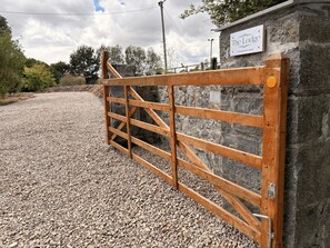A wooden gate leading to a stone wall with a sign that reads 'The Lodge.'