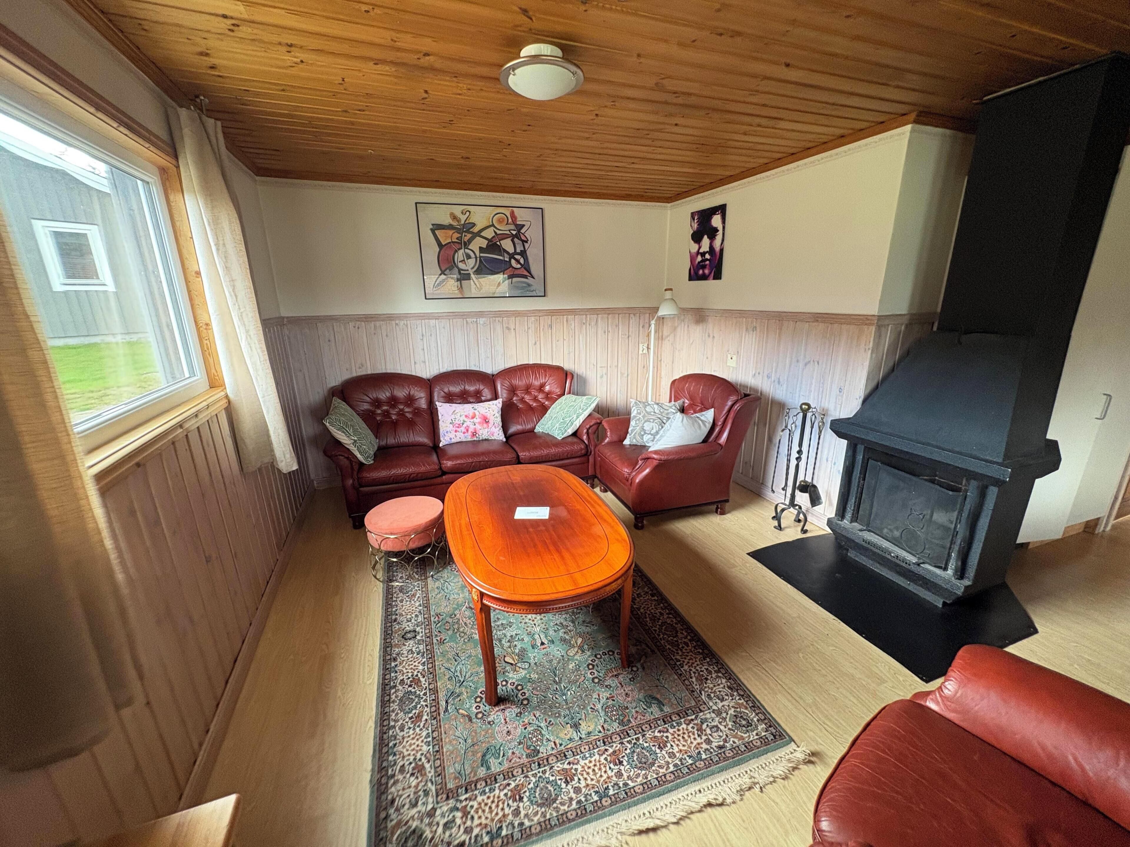 A cozy living room with a fireplace, a sofa set, a coffee table, and a patterned rug.