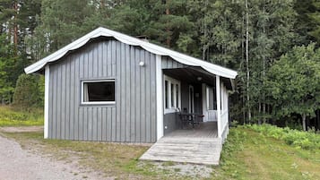 En stuga med en veranda, ett fönster och en grusgång som leder fram till den.