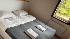 A single bed with white linens, a grey blanket, and two towels. - Lovers Nest (Värmlands län)