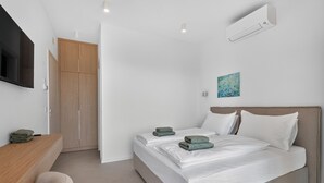 Ein modernes Schlafzimmer mit einem Bett, einem Schreibtisch und einem Fernseher.