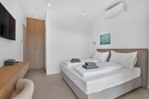 Ein modernes Schlafzimmer mit einem Bett, einem Schreibtisch und einem Fernseher.