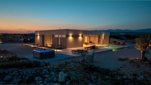 Ein modernes Haus mit Swimmingpool, Sitzgelegenheiten im Freien und einer Whirlwanne.