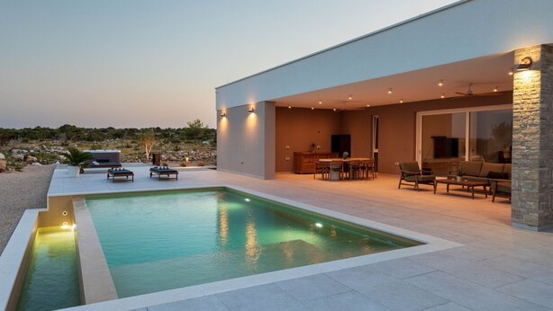 Ein moderner Poolbereich im Freien mit Terrasse, Sitzgelegenheiten und Blick auf die umliegende Landschaft.