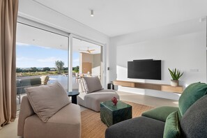 A modern living room with a sofa, armchair, and a flat-screen TV mounted on the wall. - Villa Salis with heated pool & sea view (Košljun)