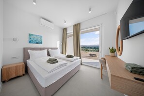 A modern hotel room with a bed, a desk, and a large window offering a view of the outdoors. - Villa Salis with heated pool & sea view (Košljun)