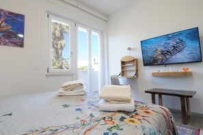 Ein Schlafzimmer mit Bett, Fernseher, Fenster und Tür.