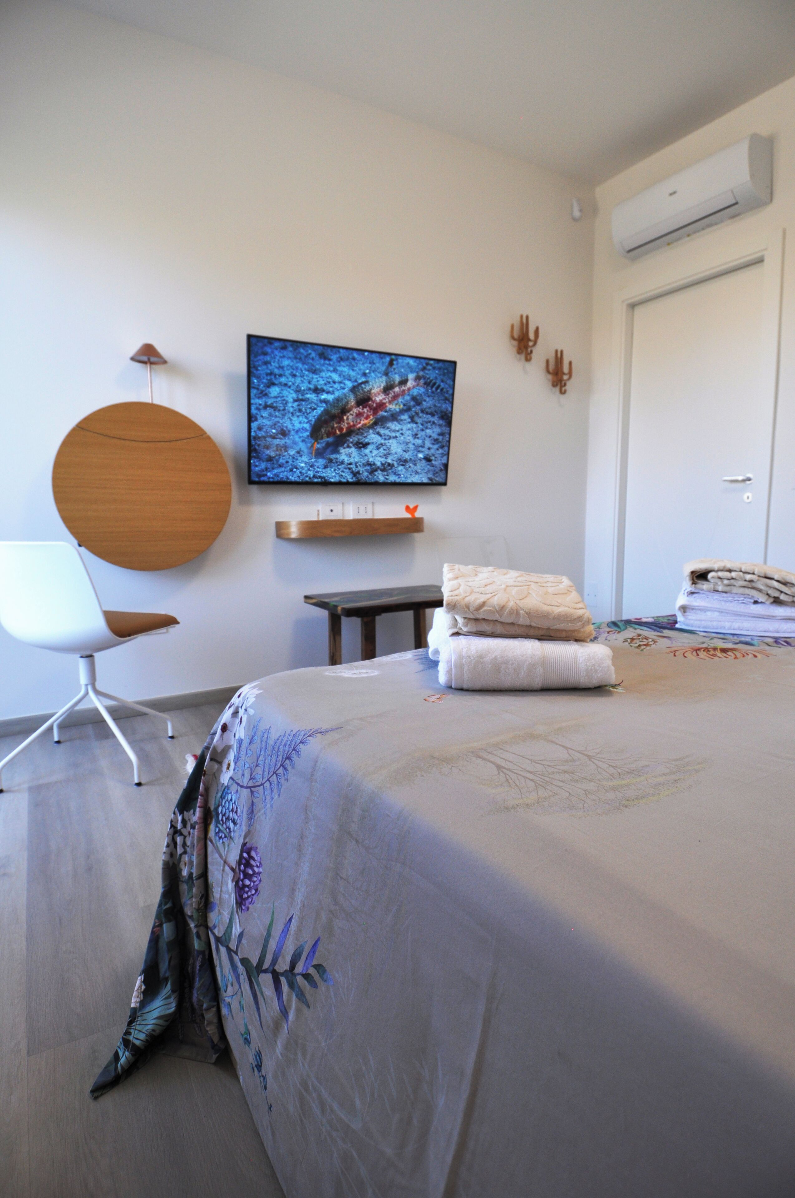 Un dormitorio con cama, una silla, televisor y puerta.