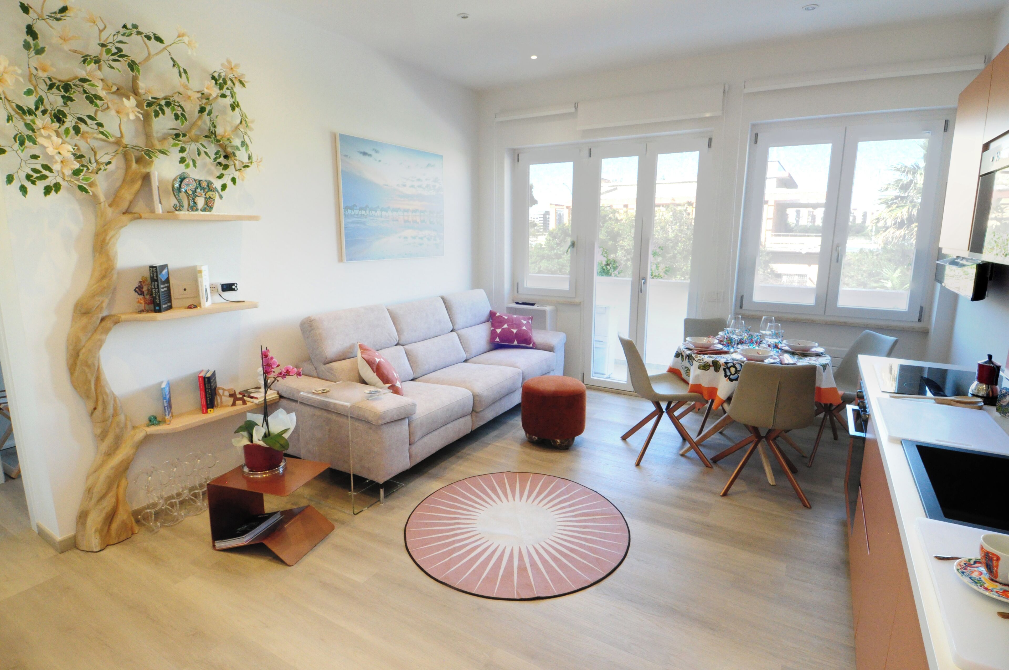 Una sala de estar moderna con un sofá, una mesa de centro y un comedor con sillas y una mesa dispuesta para una comida.