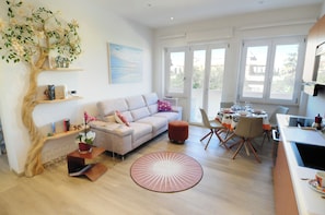 A modern living room with a sofa, a coffee table, and a dining area with chairs and a table set for a meal. - Juliet's House (Cagliari)