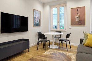 A modern living room with a flat-screen TV, a dining table with chairs, a sofa, and artwork on the walls. - Casa e Appartamento Vacanze Gallese 6 (Roma)