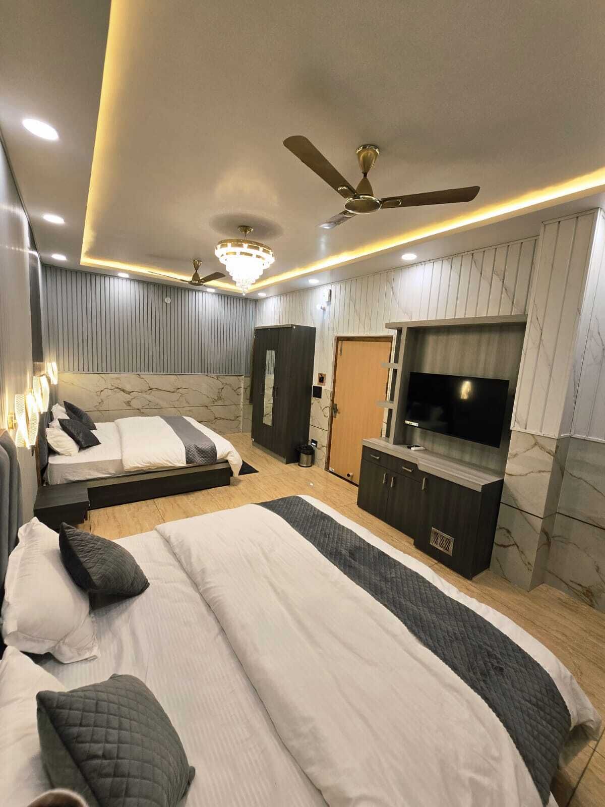 A modern bedroom with a large bed, a TV, a wardrobe, and a ceiling fan.
