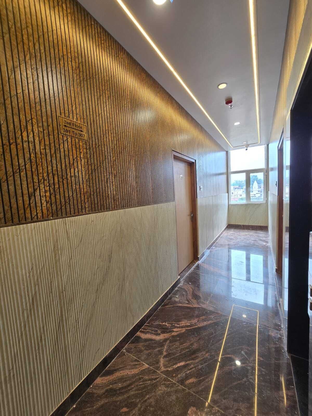 Un pasillo moderno con un revestimiento de paneles de madera, suelo de mármol y una puerta al final.