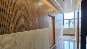 Un pasillo moderno con un revestimiento de paneles de madera, suelo de mármol y una puerta al final.