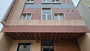 Un edificio de varios pisos con diseño moderno, que cuenta con una entrada destacada con rampa y escalera.