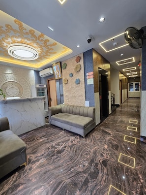A hotel lobby with a reception desk, seating area, and a marble floor. - Shri Ram Pujari Seva Sadan (Vrindavan)