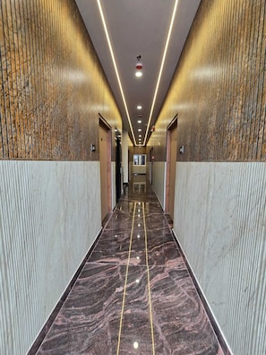 A corridor with a polished marble floor, vertical light strips, and a mirrored wall. - Shri Ram Pujari Seva Sadan (Vrindavan)
