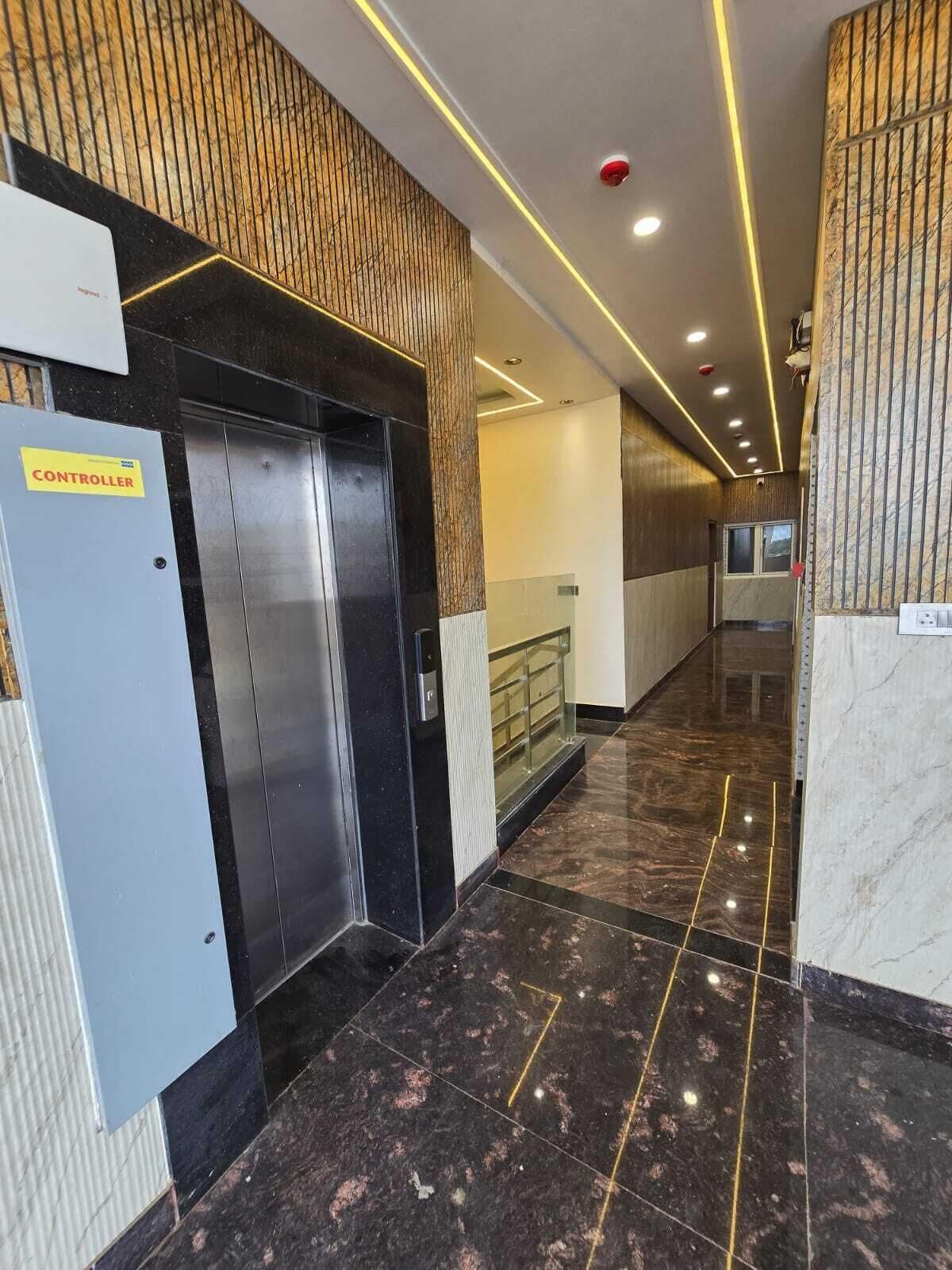Un pasillo con ascensores, un panel de control y una barandilla de vidrio.