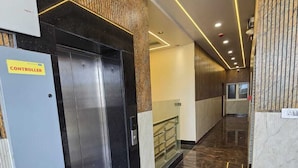 Un pasillo con ascensores, un panel de control y una barandilla de vidrio.