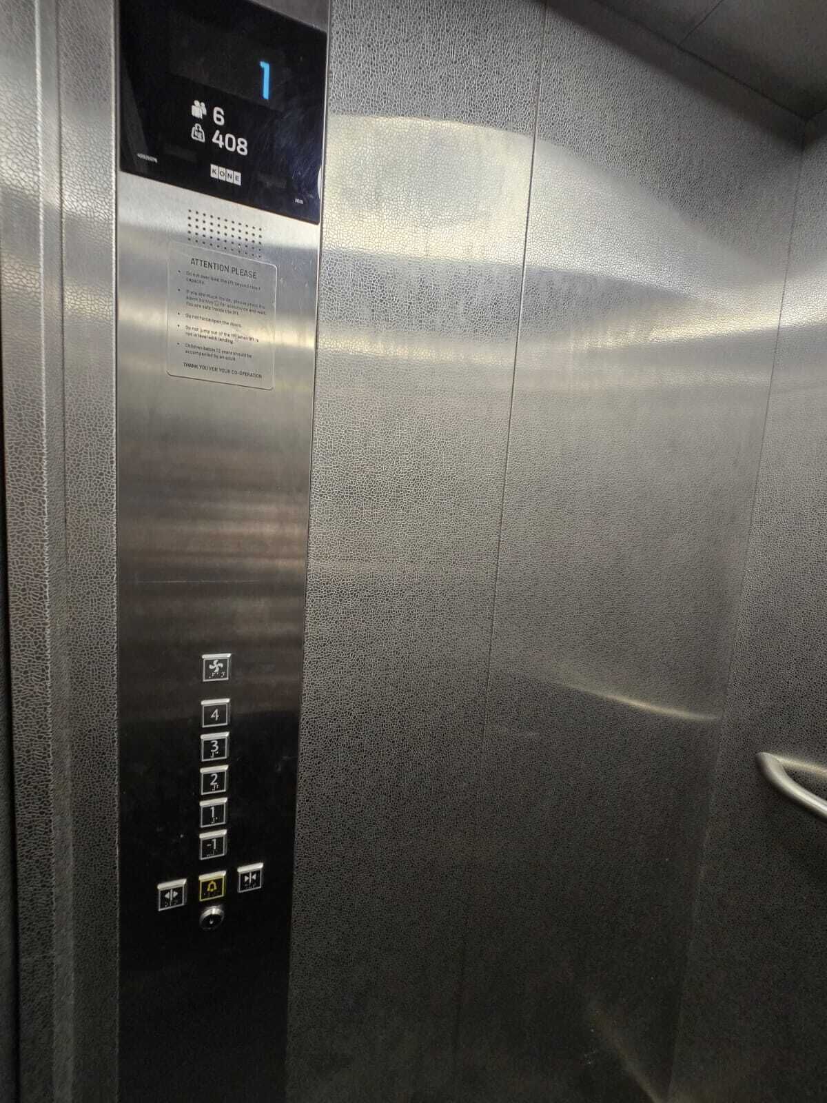 Een liftinterieur met een digitaal scherm, contactnummers voor noodgevallen en knoppen om de verdiepingen te selecteren.