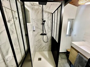 Un baño moderno con cabina de ducha, inodoro y lavamanos.