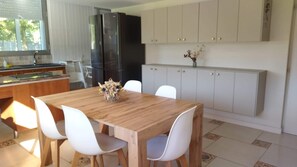 Una cocina moderna con mesa, sillas, un refrigerador y armarios.
