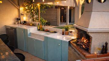 Un espace cuisine extérieur comprenant un barbecue encastré, un évier et un coin repas.