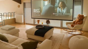 Un salon moderne doté d’un grand téléviseur à écran plat, de sièges confortables et d’un tapis décoratif.
