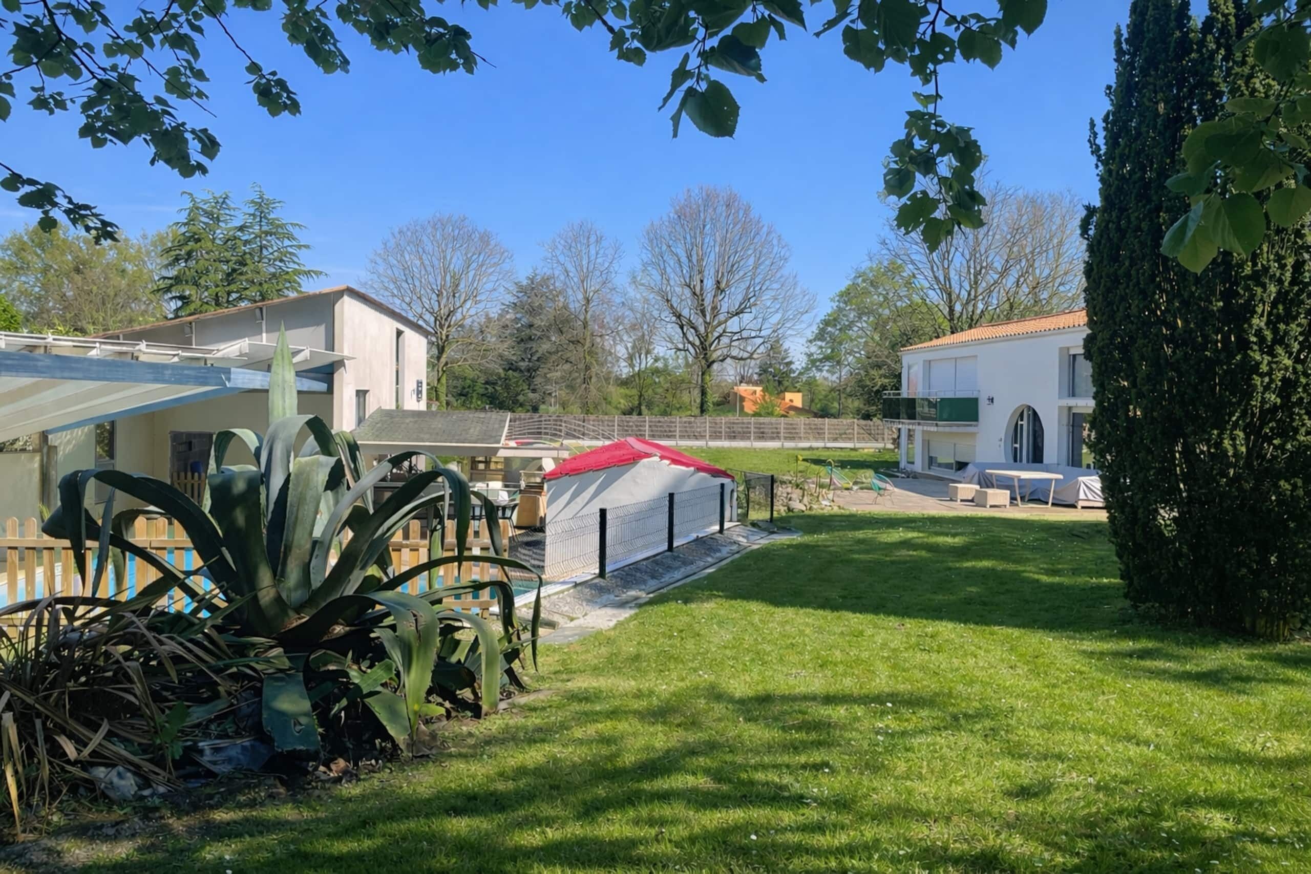 A residential area with a well-maintained lawn, a covered patio area, and a house with a red roof.