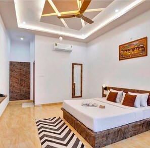 A bedroom with a bed, a ceiling fan, a wall-mounted air conditioner, and a decorative mirror. - Kings pride Aravali (Udaipur)