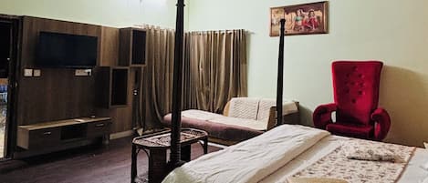 A bedroom with a bed, a red chair, a television, and a ceiling with floral patterns.