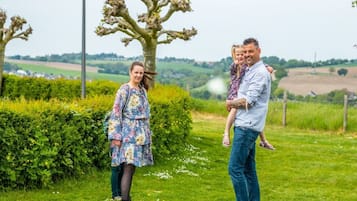 A family outdoors with a tree and a hedge in the background.