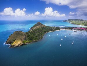 Eine Vogelperspektive einer tropischen Insel mit klarem, blauem Wasser, einem kleinen Hügel und mehreren Booten.