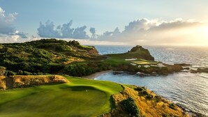 Ein Küsten-Golfplatz mit Blick auf den Ozean und einem wolkenlosen Himmel.